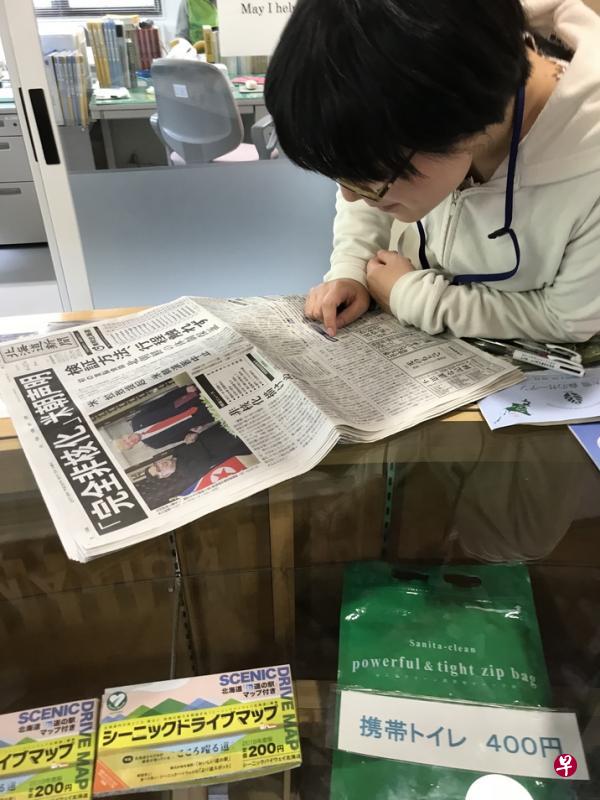 北海道一个询问中心的职员津津有味地读着在新加坡举行的特金会新闻。(读者提供) 北海道一个询问中心的职员津津有味地读着在新加坡举行的特金会新闻。(读者提供)