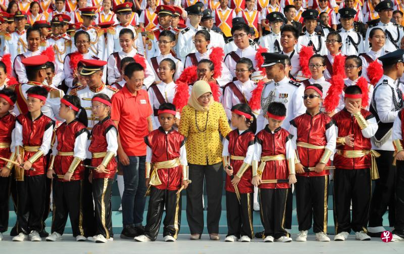 哈莉玛总统(中)昨天到滨海湾浮动舞台,观看联合学校合唱团和军操汇演的彩排后,与学生合照。(林泽锐摄) 哈莉玛总统(中)昨天到滨海湾浮动舞台,观看联合学校合唱团和军操汇演的彩排后,与学生合照。(林泽锐摄)