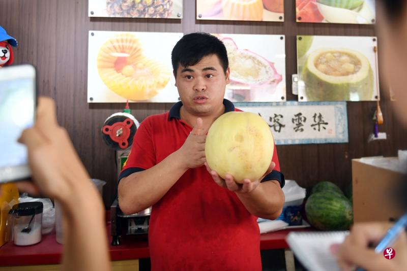 水果店员李先生出示店内售卖的蜜瓜。(蔡振鸿摄) 水果店员李先生出示店内售卖的蜜瓜。(蔡振鸿摄)
