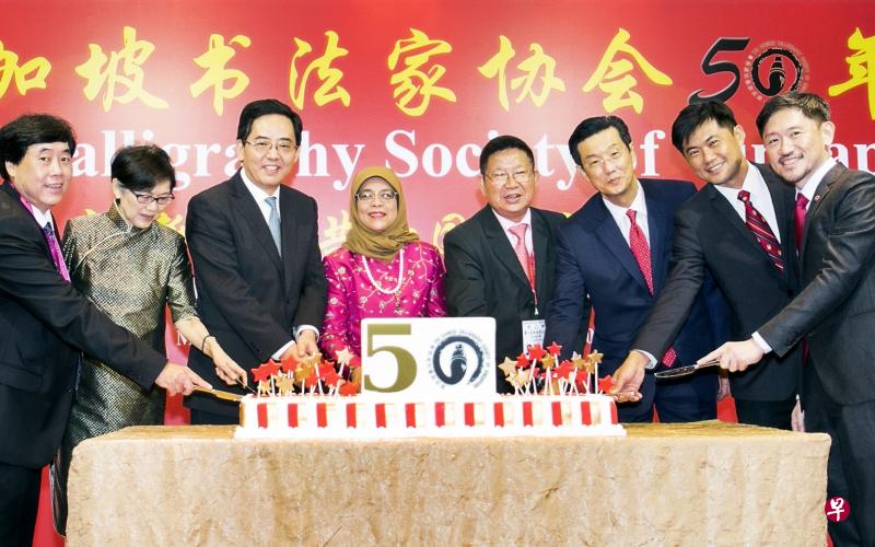 哈莉玛总统(左四)出席新加坡书法家协会创会50周年庆祝午宴。一起切蛋糕的还有新加坡书法中心董事主席杨应群(左起)、国家艺术理事会主席陈庆珠、中国驻新加坡大使洪小勇、书协会长陈声桂、日本驻新加坡大使篠田研次、人民协会总执行理事长陈国明和新加坡报业控股副执行长陈康威。(熊俊华摄) 哈莉玛总统(左四)出席新加坡书法家协会创会50周年庆祝午宴。一起切蛋糕的还有新加坡书法中心董事主席杨应群(左起)、国家艺术理事会主席陈庆珠、中国驻新加坡大使洪小勇、书协会长陈声桂、日本驻新加坡大使篠田研次、人民协会总执行理事长陈国明和新加坡报业控股副执行长陈康威。(熊俊华摄)