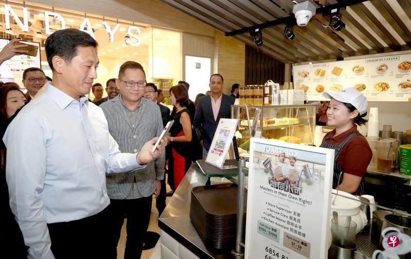 教育部长、金管局董事王乙康(左起)在面包物语区域总经理林青材陪同下,在土司工坊扫描SGQR码买咖啡。(周国威摄) 教育部长、金管局董事王乙康(左起)在面包物语区域总经理林青材陪同下,在土司工坊扫描SGQR码买咖啡。(周国威摄)
