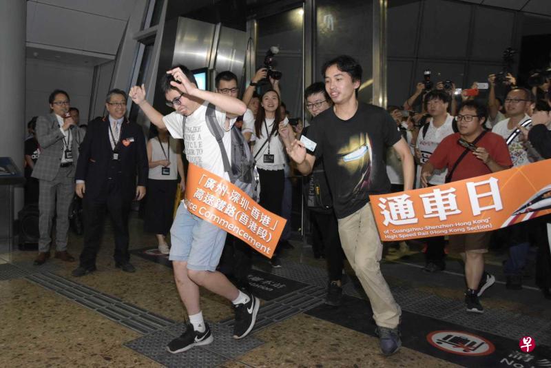 香港高铁西九龙站正式投入服务，三位高铁粉丝一早来到站门，兴奋冲过彩带。（中新社）