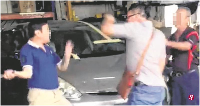 修车行老板(左)不甘被推,一度挥动手中的铁锤,但挥到一半就停下。(视频截图) 修车行老板(左)不甘被推,一度挥动手中的铁锤,但挥到一半就停下。(视频截图)