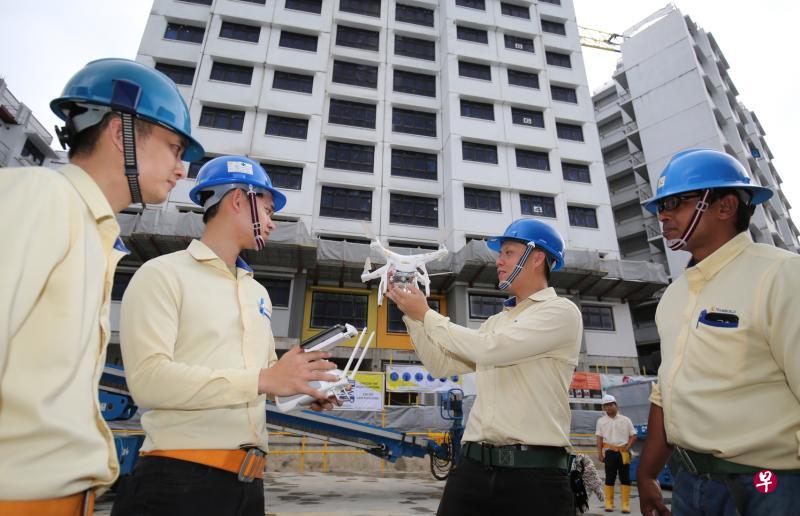 联宇建筑工程私人有限公司高级经理（环境、健康和安全）刘勇辉（右二）利用无人机介绍公司如何通过科技加强工地安全。（梁麒麟摄）