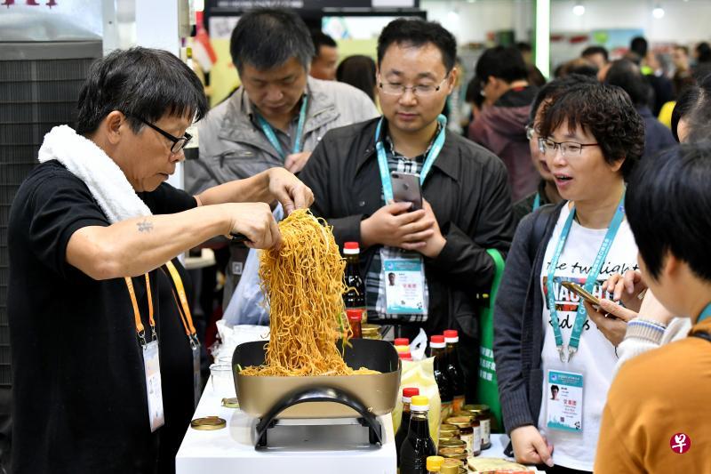 进博会上来自全球的优质农产品和各种特色美食吸引观众驻足品尝、咨询洽谈。图为11月7日,来自新加坡广祥泰私人有限公司的工作人员用公司生产的调料为参观者现场烹制炒面。(新华社) 进博会上来自全球的优质农产品和各种特色美食吸引观众驻足品尝、咨询洽谈。图为11月7日,来自新加坡广祥泰私人有限公司的工作人员用公司生产的调料为参观者现场烹制炒面。(新华社)