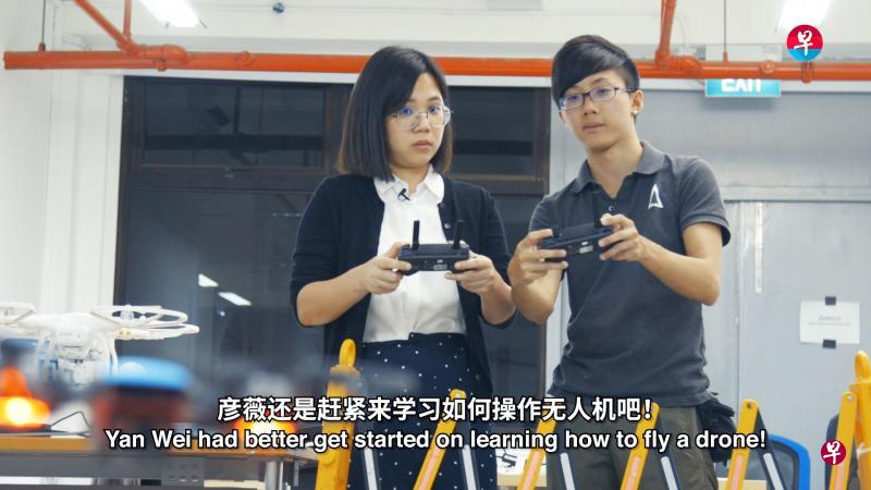 华文媒体集团新闻中心记者卓彦薇(左)在Avetics全职无人机飞行员魏铭贤的指导下,在室内试飞无人机。(视频截图) 华文媒体集团新闻中心记者卓彦薇(左)在Avetics全职无人机飞行员魏铭贤的指导下,在室内试飞无人机。(视频截图)