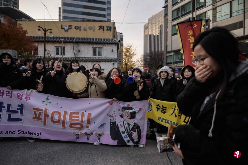 韩国首尔一名女生赴考场,许多高中生为她击鼓打气。(法新社) 韩国首尔一名女生赴考场,许多高中生为她击鼓打气。(法新社)