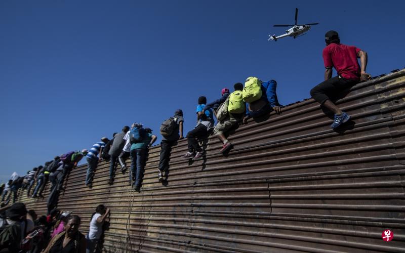 墨西哥时间星期天,在该国最北的下加利福尼亚州的蒂华纳,一批中美洲移民爬上墨美边界的围栏,要进入美国申请庇护。(法新社) 墨西哥时间星期天,在该国最北的下加利福尼亚州的蒂华纳,一批中美洲移民爬上墨美边界的围栏,要进入美国申请庇护。(法新社)