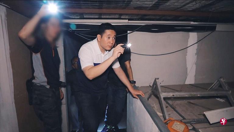安宁·阿敏拿着手电筒跟着执法人员搜查店屋单位。(视频截图 安宁·阿敏拿着手电筒跟着执法人员搜查店屋单位。(视频截图