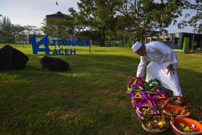 数以千计的民众昨天聚集在大亚齐的一个集体下葬墓地,悼念2004年印度洋大海啸的死难者。图为一名男子准备鲜花祭品。(法新社) 数以千计的民众昨天聚集在大亚齐的一个集体下葬墓地,悼念2004年印度洋大海啸的死难者。图为一名男子准备鲜花祭品。(法新社)
