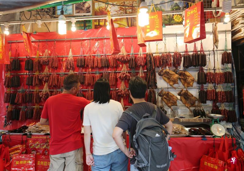 中国近来爆发非洲猪瘟，但本地售卖的腊肠猪肉主要来自美国，因此牛车水年货市场的腊味摊仍旧吸引不少顾客上门。（林国明摄）
