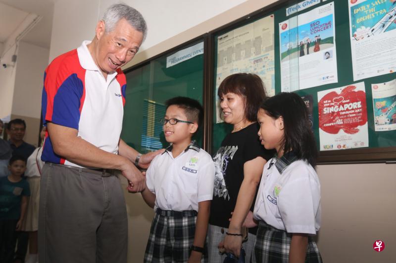 德义小学四年级学生林哲葳（左二）获颁教育储蓄品德奖，李显龙总理（左一）在颁奖礼结束后与他和他的母亲及姐姐交流。（梁伟康摄）