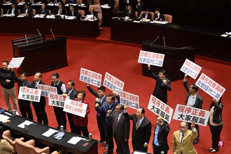 在野的国民党立委昨天在立法院举牌,抗议执政的民进党党团以多数优势决议将“同婚专法”径付二读。(法新社) 在野的国民党立委昨天在立法院举牌,抗议执政的民进党党团以多数优势决议将“同婚专法”径付二读。(法新社)
