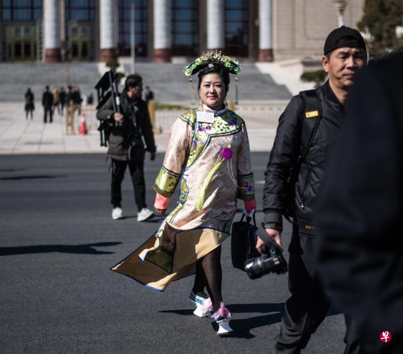 一名身穿满族传统服饰的中国人大代表步出北京人民大会堂,吸引了在停车场守候的摄影记者镜头的焦点。(法新社) 一名身穿满族传统服饰的中国人大代表步出北京人民大会堂,吸引了在停车场守候的摄影记者镜头的焦点。(法新社)