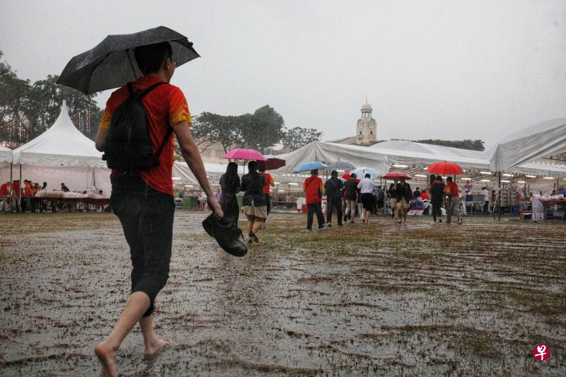 昨天傍晚时分突然下大雨,操场一度积满雨水。有校友索性脱掉鞋子,赤脚走向宴会现场。(何家俊摄) 昨天傍晚时分突然下大雨,操场一度积满雨水。有校友索性脱掉鞋子,赤脚走向宴会现场。(何家俊摄)