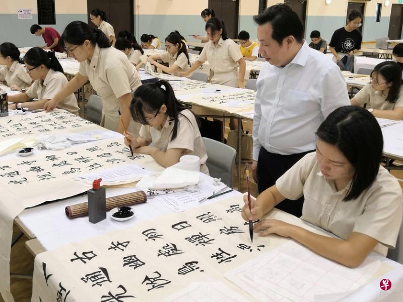 义安文化小组主任张伟伟观看参赛学生挥毫。（受访者提供）