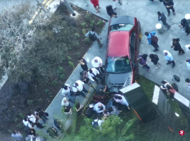 一名女子一度被卡在车底，20多名公众合力将肇祸轿车抬起，协助她脱困。（读者提供）