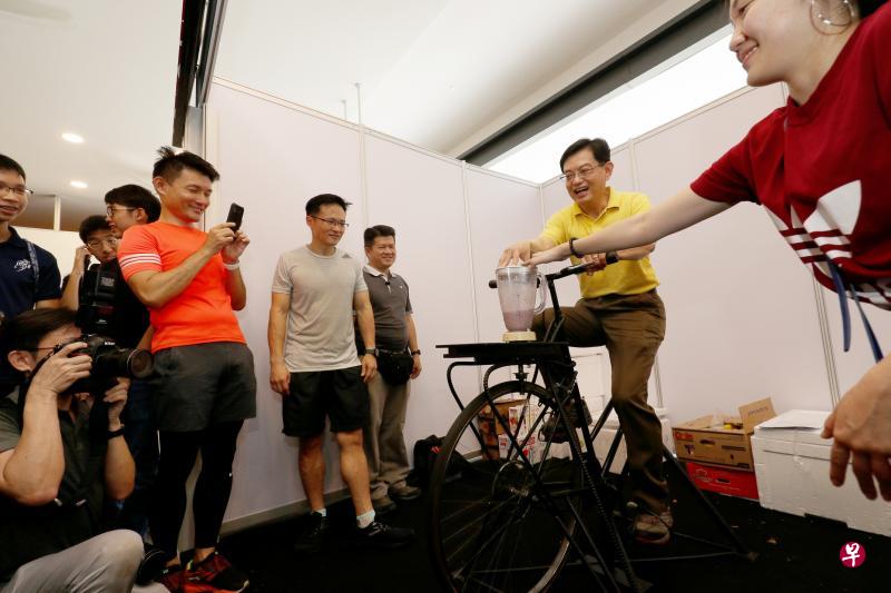 财政部长王瑞杰（右二）昨天出席淡滨尼社区活动时，尝试通过踩脚踏车发动搅拌机榨果汁。出席活动的包括同是淡滨尼集选区议员的交通部兼文化、社区及青年部高级政务次长马炎庆（左一）和东北区市长朱倍庆（左二）。（林泽锐摄）