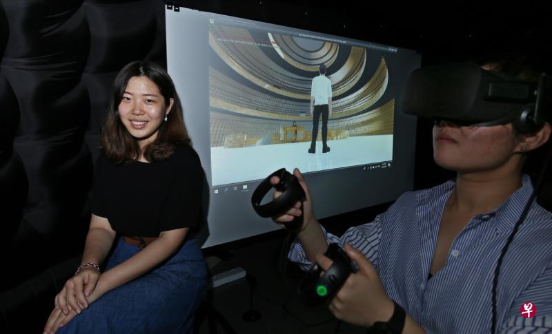 新科大建筑系学生韩景昨天在校内展示融合虚拟实境技术的“虚拟坟场”设计概念。图为一名参观者戴上虚拟实境头套，体验“虚拟坟场”空间。（梁麒麟摄）