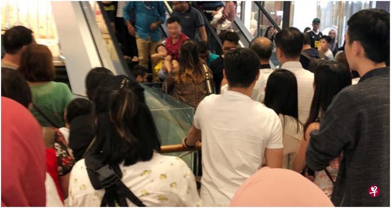 男童卡住的脚被救出后,身穿红衣的男子抱着男童走下扶梯。(读者提供) 男童卡住的脚被救出后,身穿红衣的男子抱着男童走下扶梯。(读者提供)