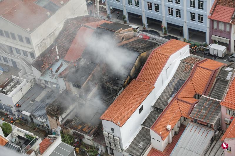 双层店屋不知何故燃起熊熊烈火，火势甚至将屋顶烧穿，消防员现场灌救，避免火势蔓延。（林国明摄）