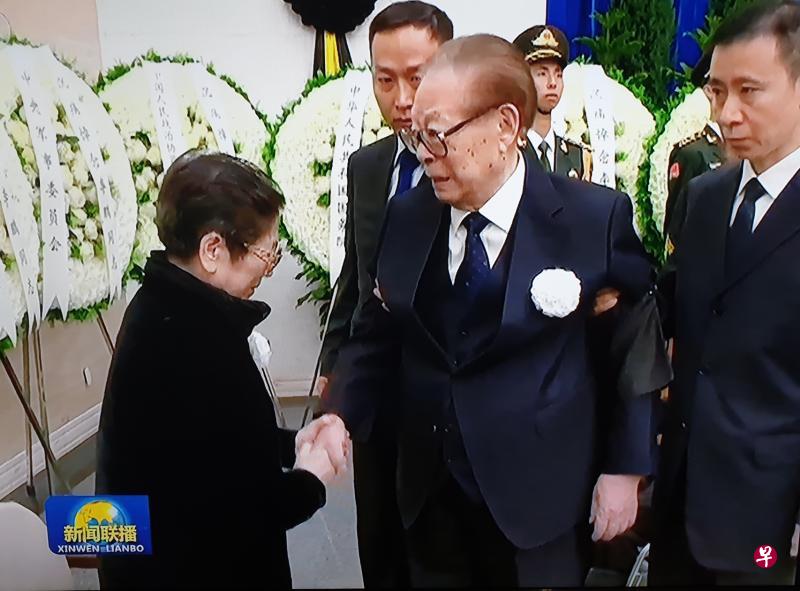 中共前总书记江泽民昨天出席李鹏遗体告别式,在两名随扈左右搀扶下与李鹏遗孀朱琳握手表示慰问。(翻拍自央视新闻联播) 中共前总书记江泽民昨天出席李鹏遗体告别式,在两名随扈左右搀扶下与李鹏遗孀朱琳握手表示慰问。(翻拍自央视新闻联播)