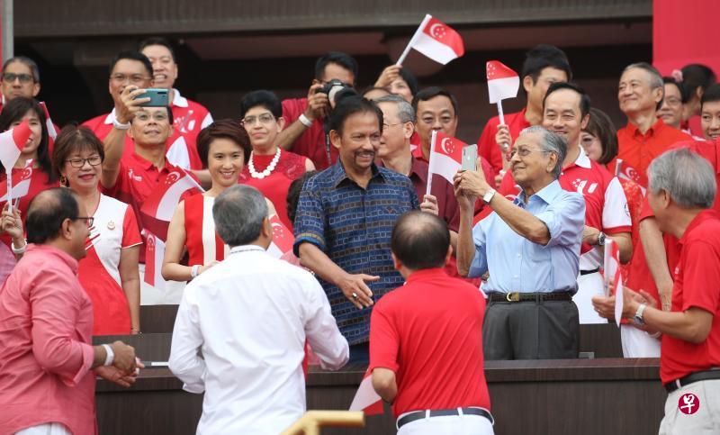 马来西亚首相马哈迪(浅蓝衣者)与文莱苏丹波基亚(深蓝衣者)在国庆庆典现场,与我国多名部长与议员打招呼,气氛友好。(谢智扬摄) 马来西亚首相马哈迪(浅蓝衣者)与文莱苏丹波基亚(深蓝衣者)在国庆庆典现场,与我国多名部长与议员打招呼,气氛友好。(谢智扬摄)