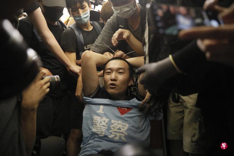 《环球时报》记者付国豪8月13日晚在香港机场曾被示威者绑在行李车围殴。（美联社）