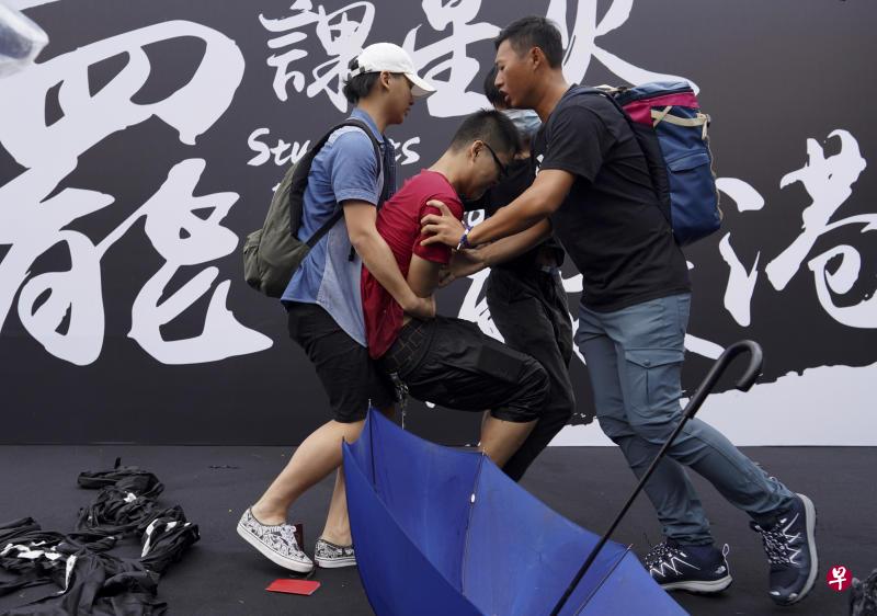 一名大陆学生冲上台试图撕毁现场的横额,被周围的学生劝拦。(美联社) 一名大陆学生冲上台试图撕毁现场的横额,被周围的学生劝拦。(美联社)