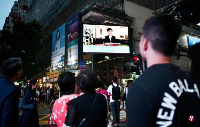 香港市民昨天在街上的一个大荧幕前驻足观看特首林郑月娥发表的电视录影讲话。她在讲话中表示,希望提出的四项行动可以打破困局,以对话代替对立。(法新社) 香港市民昨天在街上的一个大荧幕前驻足观看特首林郑月娥发表的电视录影讲话。她在讲话中表示,希望提出的四项行动可以打破困局,以对话代替对立。(法新社)