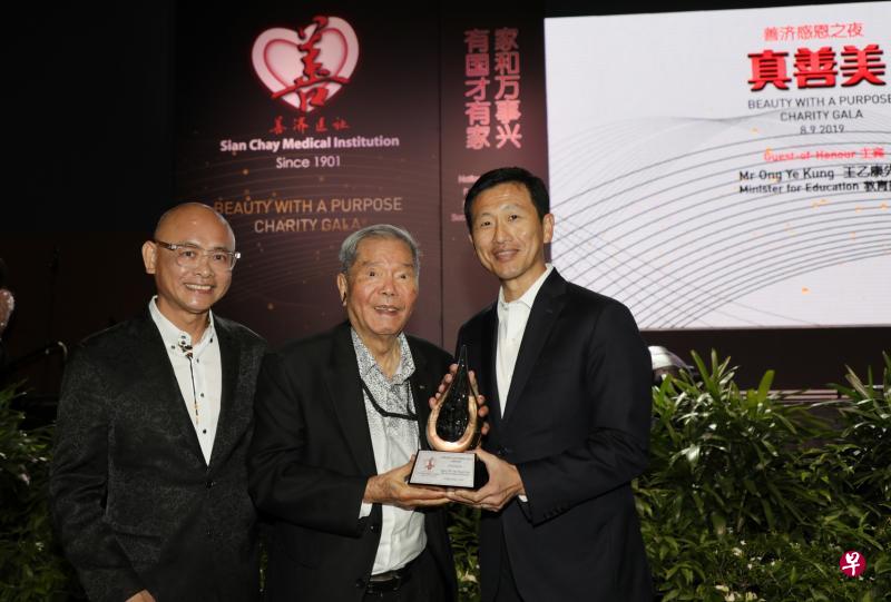 教育部长王乙康走下讲台,将善济“特别贡献奖”奖座颁给94岁的新加坡鳄鱼牌公司创办人陈贤进博士(中)。左为善济主席卓顺发。(林国明摄) 教育部长王乙康走下讲台,将善济“特别贡献奖”奖座颁给94岁的新加坡鳄鱼牌公司创办人陈贤进博士(中)。左为善济主席卓顺发。(林国明摄)