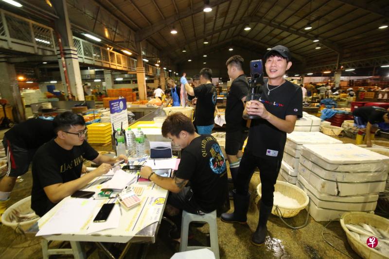 纪志忠直播时,现场有至少10名员工帮忙,分别负责记录、准备、摆放,以及在鱼卖出后立刻加工包装。(梁麒麟摄) 纪志忠直播时,现场有至少10名员工帮忙,分别负责记录、准备、摆放,以及在鱼卖出后立刻加工包装。(梁麒麟摄)