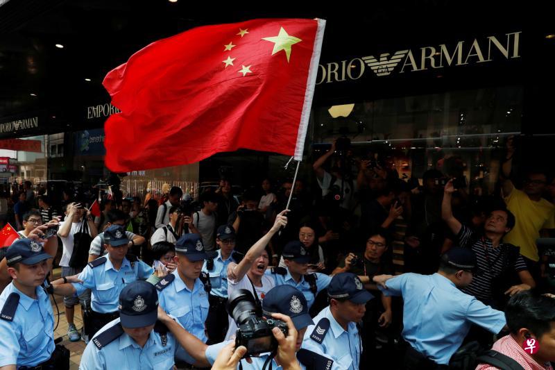 有香港爱国人士昨天到尖沙咀唱国歌,结果引来黑衣抗争者狙击,爱国人士最后在大批警员团团包围保护下离开。(路透社) 有香港爱国人士昨天到尖沙咀唱国歌,结果引来黑衣抗争者狙击,爱国人士最后在大批警员团团包围保护下离开。(路透社)