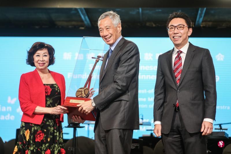 李显龙总理(中)昨晚在新加坡华乐团2019年筹款晚宴暨音乐会上向晚宴筹委会主席、荣誉国务资政吴作栋的夫人陈子玲(左)颁发纪念品。同台的是新加坡华乐团董事主席吴绍均(右)。(梁伟康摄) 李显龙总理(中)昨晚在新加坡华乐团2019年筹款晚宴暨音乐会上向晚宴筹委会主席、荣誉国务资政吴作栋的夫人陈子玲(左)颁发纪念品。同台的是新加坡华乐团董事主席吴绍均(右)。(梁伟康摄)