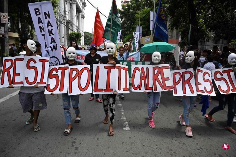 菲律宾高庭目前正在审理前总统马可斯的儿子小马科斯挑战2016年副总统选举结果的申请。戴上面具的群众8日在马尼拉高等法院前游行,高举标语牌和旗帜支持当选的菲副总统罗布雷多。(法新社) 菲律宾高庭目前正在审理前总统马可斯的儿子小马科斯挑战2016年副总统选举结果的申请。戴上面具的群众8日在马尼拉高等法院前游行,高举标语牌和旗帜支持当选的菲副总统罗布雷多。(法新社)