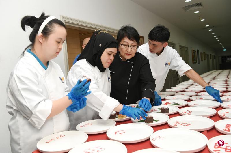 本地著名美食家温美玉(右二)为特别需求者协会的烘焙班学生举办课程,指导他们做糕点,学生们昨晚让公益金颁奖礼的来宾品尝他们的手艺。(海峡时报) 本地著名美食家温美玉(右二)为特别需求者协会的烘焙班学生举办课程,指导他们做糕点,学生们昨晚让公益金颁奖礼的来宾品尝他们的手艺。(海峡时报)