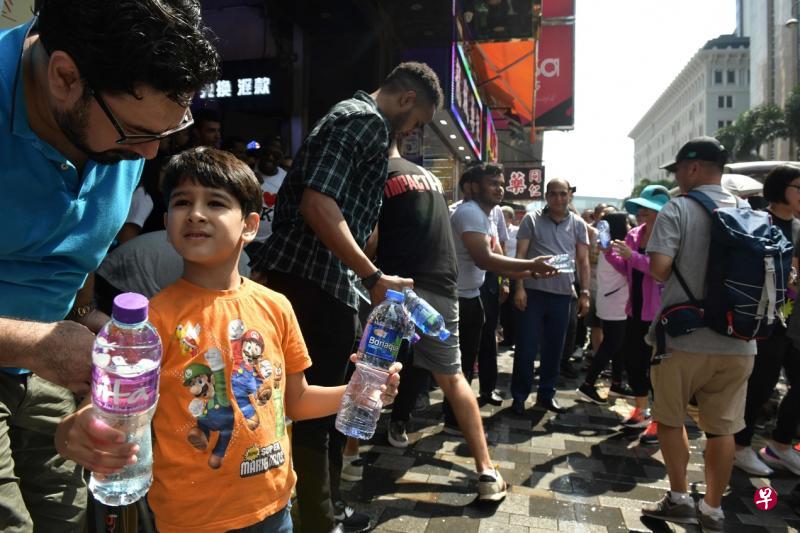 香港多名南亚裔人士昨天在尖沙咀重庆大厦门口派送瓶装水给示威者。重庆大厦以廉价酒店、咖喱餐馆等为特点,也被视为香港少数族裔的主要聚集地。(法新社) 香港多名南亚裔人士昨天在尖沙咀重庆大厦门口派送瓶装水给示威者。重庆大厦以廉价酒店、咖喱餐馆等为特点,也被视为香港少数族裔的主要聚集地。(法新社)