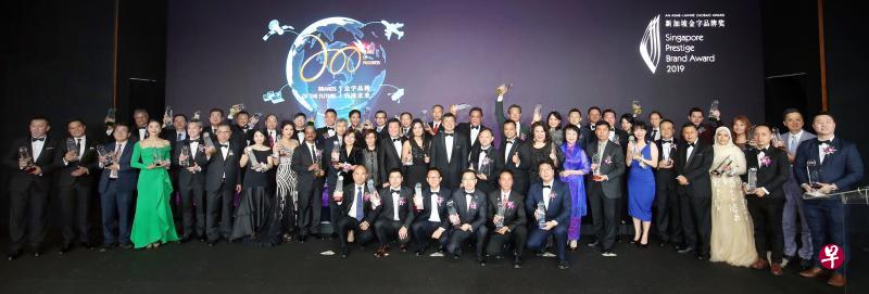 2019年新加坡金字品牌奖颁奖礼昨晚举行，得奖品牌代表与总理公署部长、全国职工总会秘书长黄志明（第二排中）及出席嘉宾合照。他们包括金字品牌奖筹委会联合主席、新加坡报业控股华文媒体集团新闻中心副总编辑吴新慧（第二排左边第12起）、《联合早报》兼《联合晚报》总编辑吴新迪、金字品牌奖荣誉榜得主新肤副董事长李彩云、成名品牌奖总冠军FotoHub集团总裁陈运隆、中小企业商会会长王腾忆、金字品牌奖中国筹委会联合主席范文瑂，以及金字品牌奖筹委会主席周丽青。（邝启聪摄）