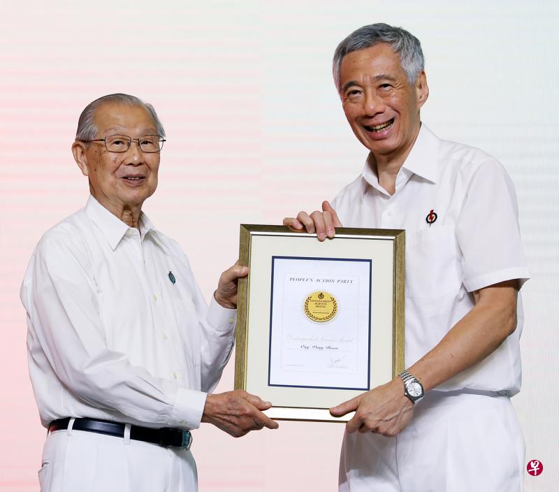 第一代内阁部长王邦文（左）在行动党大会上，从行动党秘书长李显龙总理手中接过殊功奖章。（林泽锐摄）