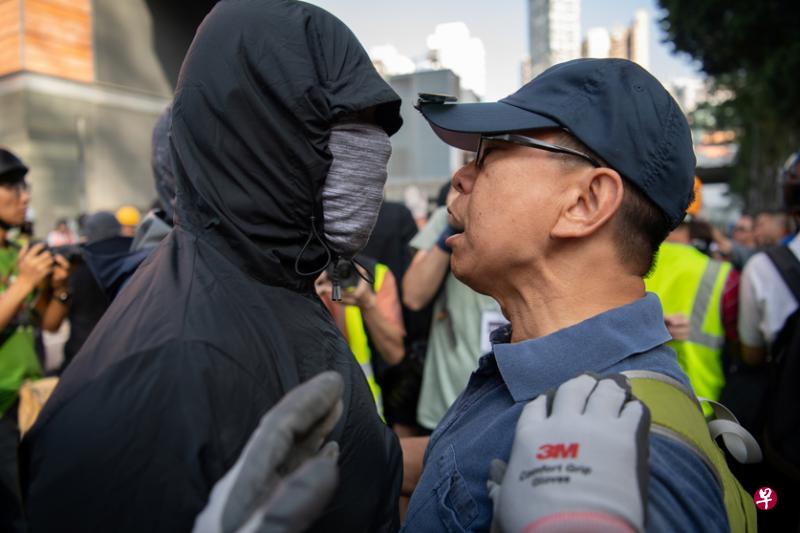 一群市民清理路障期间被黑衣人投掷汽油弹，气得破口大骂。（法新社）