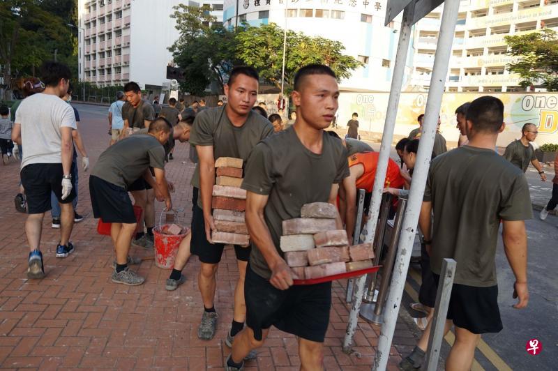 穿着便装的驻港部队官兵昨天下午走出九龙塘九龙东军营,和市民一起清理附近街上的路障。(法新社) 穿着便装的驻港部队官兵昨天下午走出九龙塘九龙东军营,和市民一起清理附近街上的路障。(法新社)