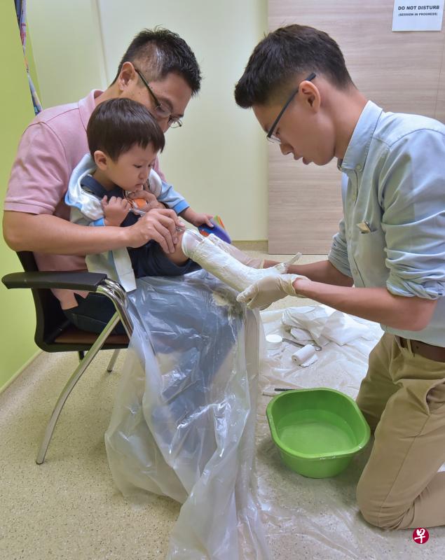 竹脚妇幼医院义肢矫形师黄勇杰(右)为小患者李宇乐脚上的石膏取样后,就可在院内开始制作踝足矫形器。陪伴孩子的是父亲李国伟。(特约林新泰摄) 竹脚妇幼医院义肢矫形师黄勇杰(右)为小患者李宇乐脚上的石膏取样后,就可在院内开始制作踝足矫形器。陪伴孩子的是父亲李国伟。(特约林新泰摄)