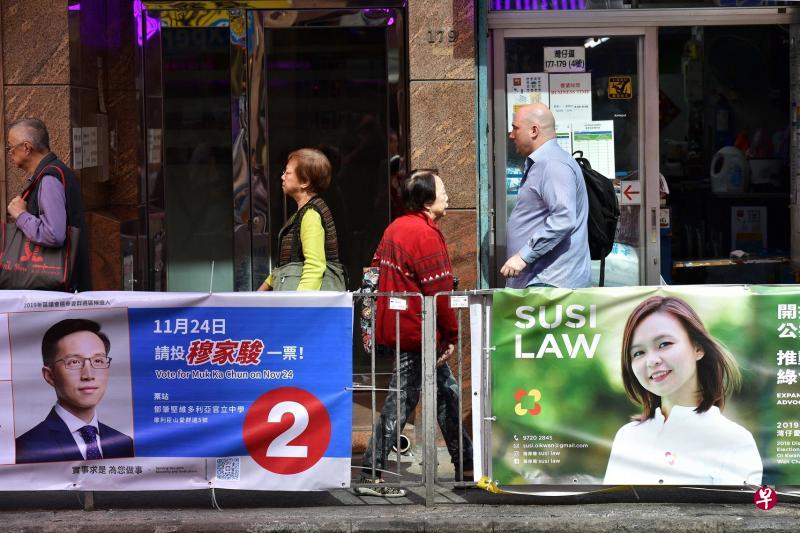 香港区议会选举候选人穆家骏与罗伟珊张挂在湾仔街头的竞选宣传海报。两人分属建制派与民主派。(法新社) 香港区议会选举候选人穆家骏与罗伟珊张挂在湾仔街头的竞选宣传海报。两人分属建制派与民主派。(法新社)