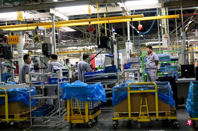 工人们9月26日在北汽福田汽车的发动机零件装配区工作。(法新社) 工人们9月26日在北汽福田汽车的发动机零件装配区工作。(法新社)