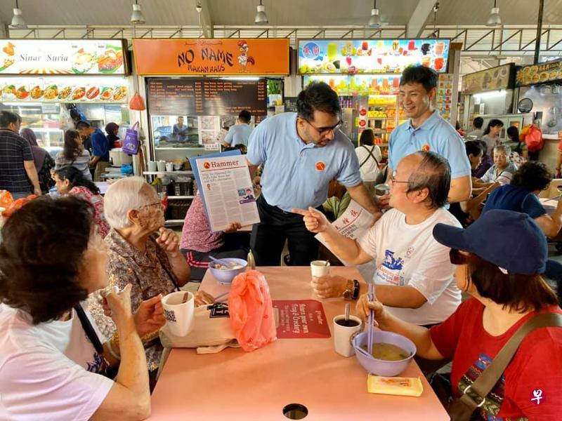 工人党党魁毕丹星（站立者左）亲自带着该党年轻新面孔Jamus Lim（站立者右），一同售卖党报。工人党此次吸引到的“新生代”也属白领专业人士行列。（黄伟曼摄）