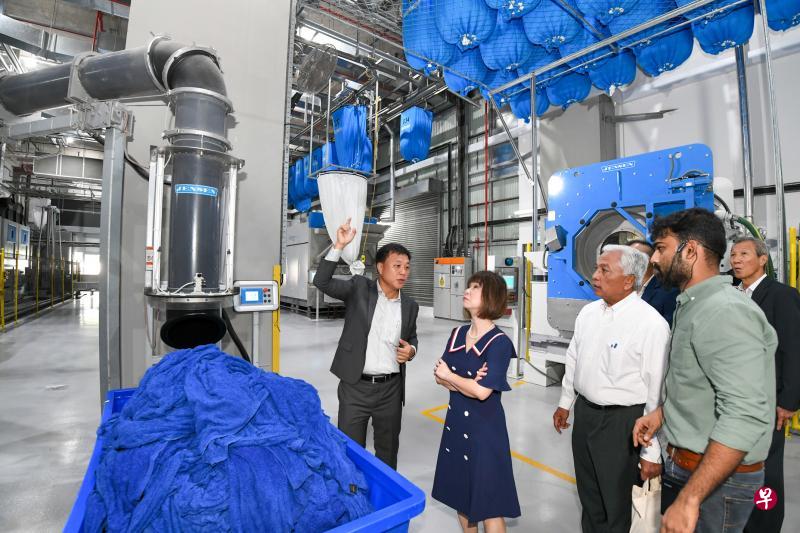 八百控股总裁李清财(左一)向卫生部兼环境及水源部高级政务部长许连碹博士(左二)讲解抽吸系统可直接将衣物抽吸装入工业烘干机器里。(八百控股提供) 八百控股总裁李清财(左一)向卫生部兼环境及水源部高级政务部长许连碹博士(左二)讲解抽吸系统可直接将衣物抽吸装入工业烘干机器里。(八百控股提供)