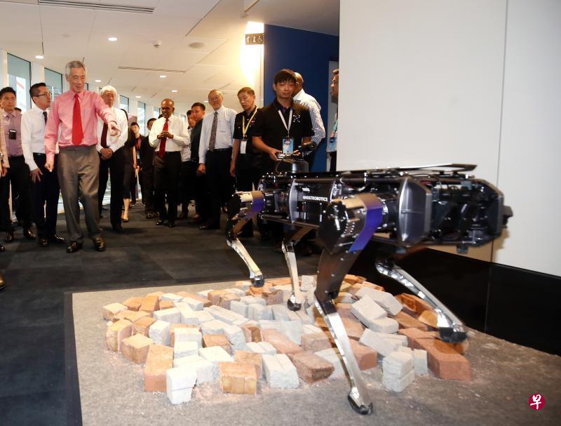 李显龙总理(粉红衣者)向内政科技局人员了解四脚机器人Rover-X如何在崎岖不平的地势行走,在危险环境中执行搜救任务。国务资政兼国家安全统筹部长张志贤(后排左三)和内政部长兼律政部长尚穆根(后排左四)陪同参观。(陈渊庄摄) 李显龙总理(粉红衣者)向内政科技局人员了解四脚机器人Rover-X如何在崎岖不平的地势行走,在危险环境中执行搜救任务。国务资政兼国家安全统筹部长张志贤(后排左三)和内政部长兼律政部长尚穆根(后排左四)陪同参观。(陈渊庄摄)