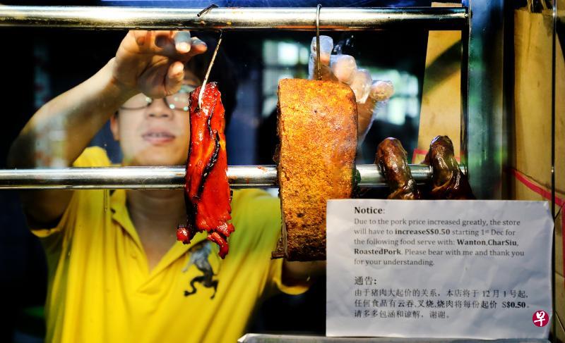 大巴窑一家咖啡店烧腊摊的摊主吴子豪在摊位前张贴告示,宣布从12月1日起把含有云吞、叉烧和烧肉的食品价格调高5角钱。(陈斌勤摄) 大巴窑一家咖啡店烧腊摊的摊主吴子豪在摊位前张贴告示,宣布从12月1日起把含有云吞、叉烧和烧肉的食品价格调高5角钱。(陈斌勤摄)
