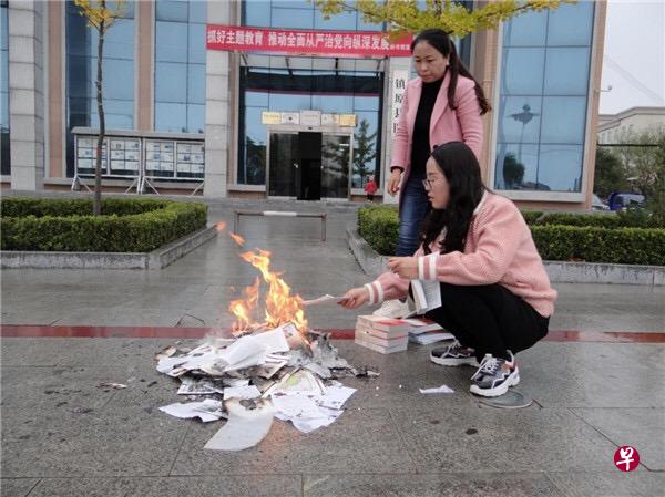两名工作人员在销毁被下架的书籍,可见背后是镇原县图书馆。(互联网) 两名工作人员在销毁被下架的书籍,可见背后是镇原县图书馆。(互联网)