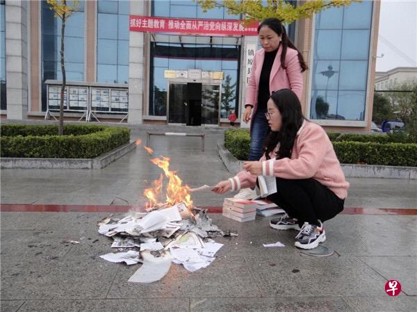 两名工作人员在销毁被下架的书籍,可见背后是镇原县图书馆。(互联网) 两名工作人员在销毁被下架的书籍,可见背后是镇原县图书馆。(互联网)